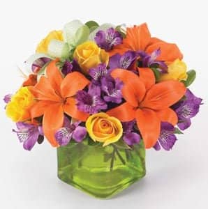Green cube vase arrangement with orange lily, purple Peruvian lilies, yellow spray roses